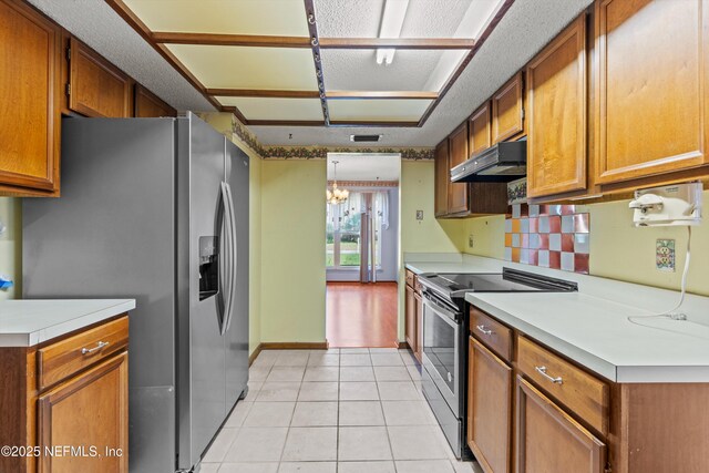 1083 Kings Rd, Neptune Beach, FL 32266 - kitchen with stainless steel appliances, under cabinet range hood, light countertops, a chandelier, and brown cabinetry