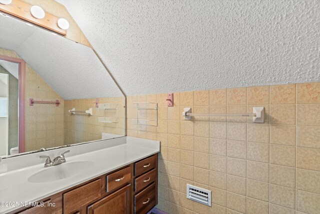 1083 Kings Rd, Neptune Beach, FL 32266 - bathroom with vaulted ceiling, vanity, and tile walls