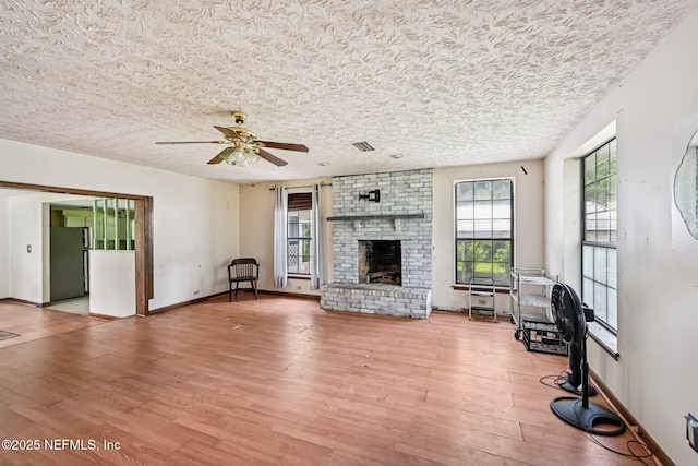 2259 Marlee Rd S, Jacksonville, FL 32259 - unfurnished living room featuring light wood-style floors, a brick fireplace, a ceiling fan, and a textured ceiling
