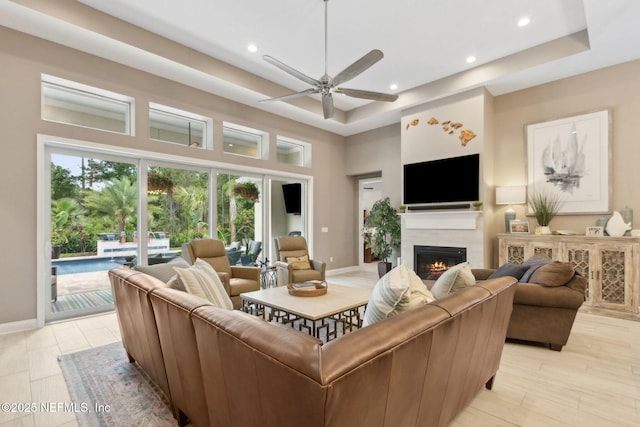 95196 Golden Glow Dr, Fernandina Beach, FL 32034 - living area with a warm lit fireplace, ceiling fan, a raised ceiling, recessed lighting, and a high ceiling