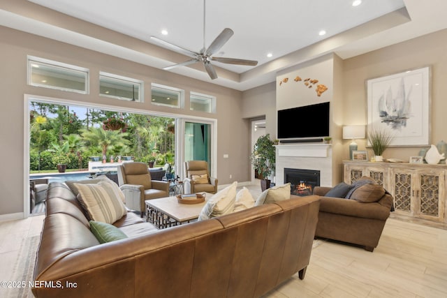 95196 Golden Glow Dr, Fernandina Beach, FL 32034 - living room featuring a raised ceiling, a ceiling fan, a glass covered fireplace, recessed lighting, and a high ceiling
