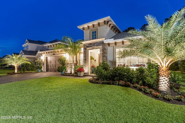 95196 Golden Glow Dr, Fernandina Beach, FL 32034 - view of front facade with stone siding, driveway, a yard, an attached garage, and stucco siding
