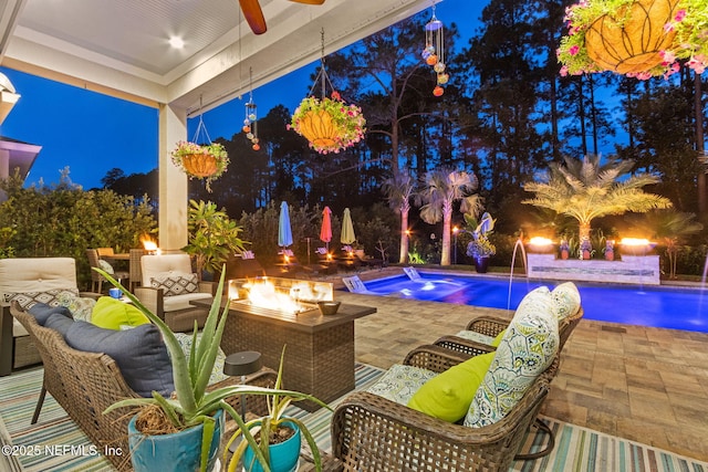 95196 Golden Glow Dr, Fernandina Beach, FL 32034 - pool at night with an outdoor living space with a fire pit, a patio area, an outdoor pool, and ceiling fan