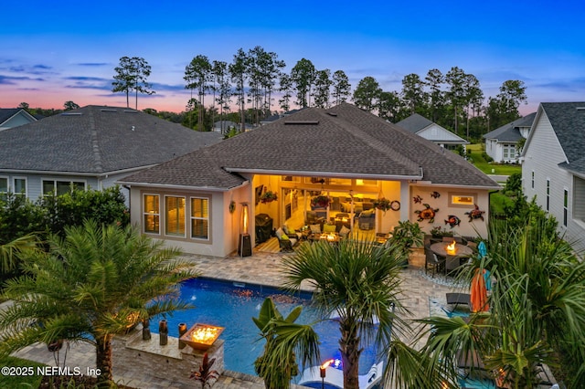 95196 Golden Glow Dr, Fernandina Beach, FL 32034 - back of property at dusk featuring a patio area, a fire pit, an outdoor pool, and an attached garage