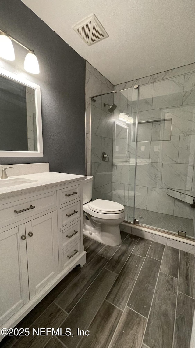 2664 SW 14th Dr Unit 325, Gainesville, FL 32608 - bathroom with vanity, a stall shower, wood finish floors, and a textured wall