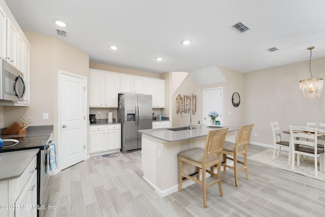 30 Yeti Ct, Saint Augustine, FL 32092 - kitchen featuring stainless steel appliances, light wood-type flooring, white cabinetry, a kitchen breakfast bar, and an island with sink