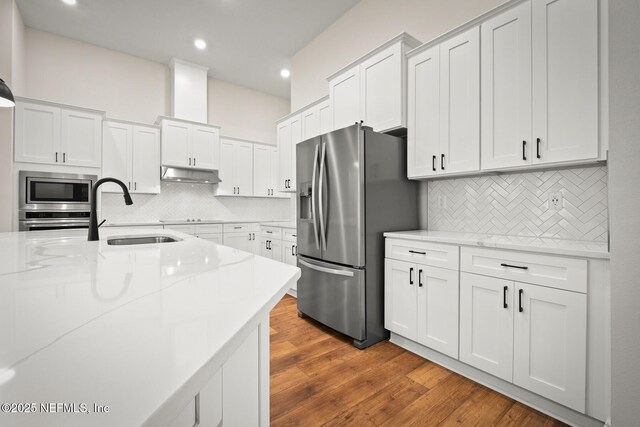 36250 Pitch Ln, Hilliard, FL 32046 - kitchen featuring appliances with stainless steel finishes, under cabinet range hood, white cabinetry, tasteful backsplash, and recessed lighting