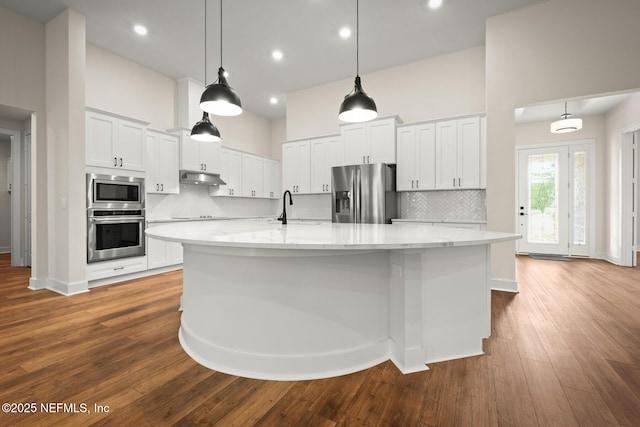 36250 Pitch Ln, Hilliard, FL 32046 - kitchen with stainless steel appliances, white cabinetry, backsplash, a large island, and dark wood finished floors