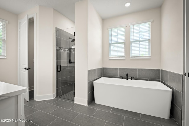 36250 Pitch Ln, Hilliard, FL 32046 - full bath with healthy amount of natural light, a soaking tub, a stall shower, tile patterned floors, and tile walls