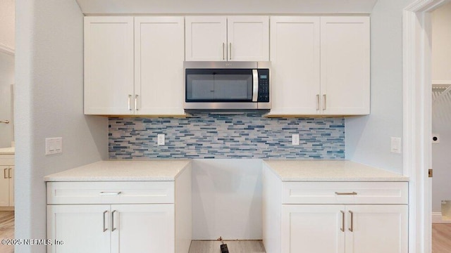 99 Sloganeer Trl, Palm Coast, FL 32164 - kitchen featuring stainless steel microwave, light countertops, backsplash, and white cabinetry