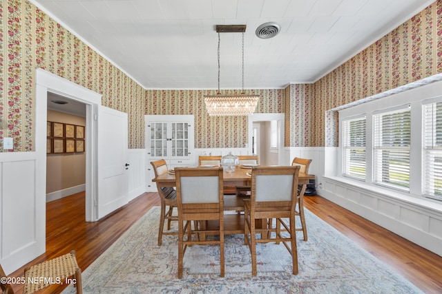117 Parshley St SW, Live Oak, FL 32064 - dining room with wood finished floors, a chandelier, a wainscoted wall, wallpapered walls, and ornamental molding