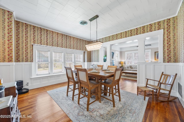 117 Parshley St SW, Live Oak, FL 32064 - dining room featuring decorative columns, wallpapered walls, crown molding, hardwood / wood-style flooring, and wainscoting