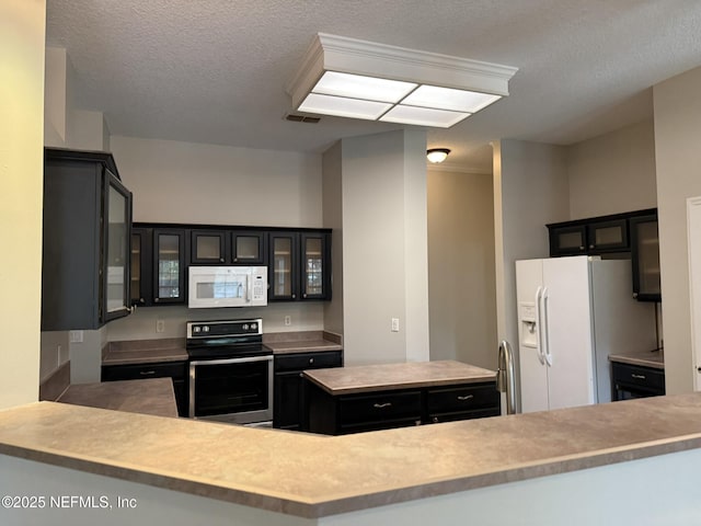 1032 Durbin Parke Dr, Jacksonville, FL 32259 - kitchen with white appliances, dark cabinetry, a textured ceiling, glass insert cabinets, and a center island