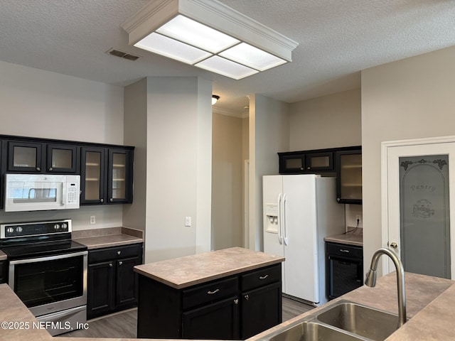 1032 Durbin Parke Dr, Jacksonville, FL 32259 - kitchen featuring white appliances, dark cabinetry, a textured ceiling, a kitchen island, and wood finished floors