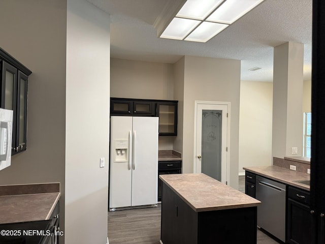 1032 Durbin Parke Dr, Jacksonville, FL 32259 - kitchen featuring white refrigerator with ice dispenser, dishwasher, dark cabinetry, and a center island