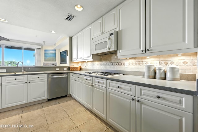 2201 Windjammer Ln, Saint Augustine, FL 32084 - kitchen with white appliances, light tile patterned floors, decorative backsplash, white cabinetry, and recessed lighting