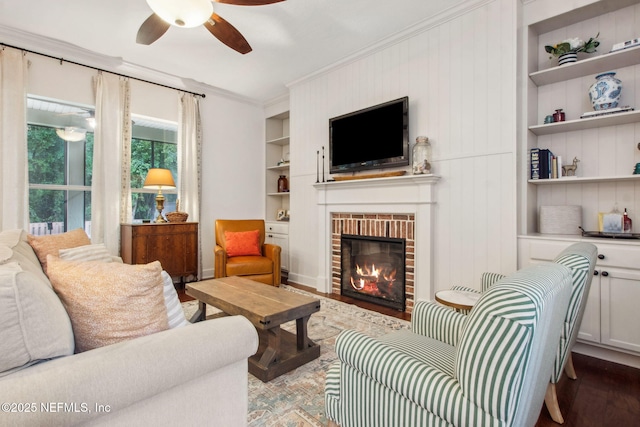 85488 Sagaponack Dr, Fernandina Beach, FL 32034 - living room featuring built in shelves, a ceiling fan, crown molding, a fireplace, and wood finished floors