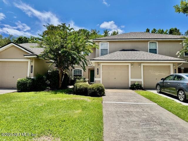 1810 Green Springs Cir Unit B, Fleming Island, FL 32003 - view of front of house featuring stucco siding, a front lawn, a garage, and concrete driveway