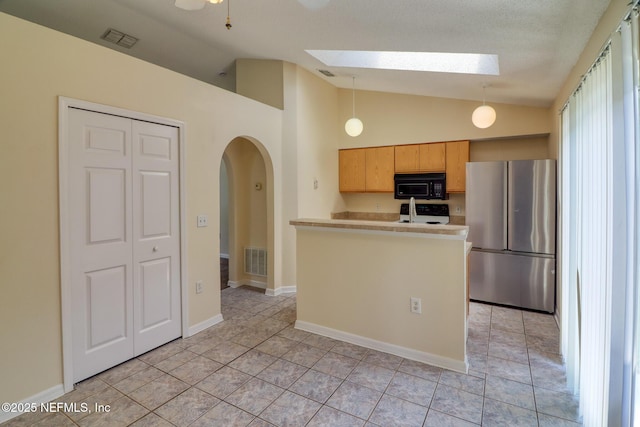 3371 Net Ct, Jacksonville, FL 32277 - kitchen with freestanding refrigerator, black microwave, a skylight, vaulted ceiling, and arched walkways