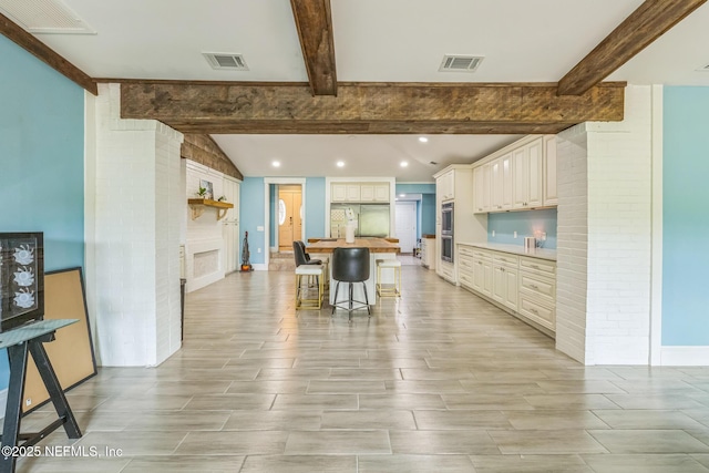 10268 Lake View Rd W, Jacksonville, FL 32225 - kitchen featuring a fireplace, a kitchen bar, a center island, light wood-style floors, and brick wall