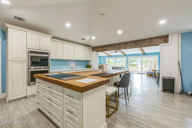 10268 Lake View Rd W, Jacksonville, FL 32225 - kitchen with butcher block counters, black electric cooktop, double oven, a kitchen breakfast bar, and white cabinetry