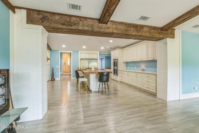 10268 Lake View Rd W, Jacksonville, FL 32225 - kitchen featuring beam ceiling, butcher block counters, a kitchen bar, light wood-style floors, and a kitchen island