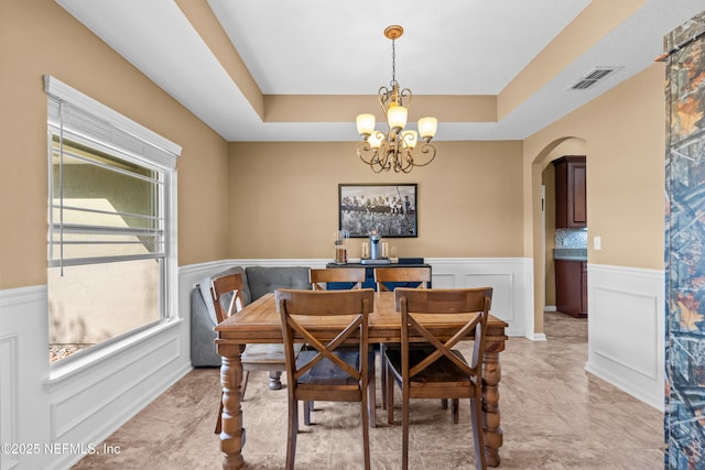 321 Palazzo Cir, Saint Augustine, FL 32092 - dining room featuring wainscoting, a tray ceiling, arched walkways, a chandelier, and a decorative wall