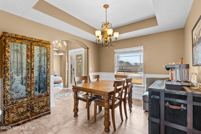 321 Palazzo Cir, Saint Augustine, FL 32092 - tiled dining space featuring a chandelier, arched walkways, a tray ceiling, and wainscoting