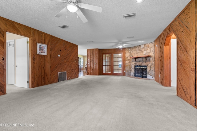 6032 Bob Kirkland Rd, Macclenny, FL 32063 - unfurnished living room with wood walls, ceiling fan, carpet flooring, a textured ceiling, and a stone fireplace