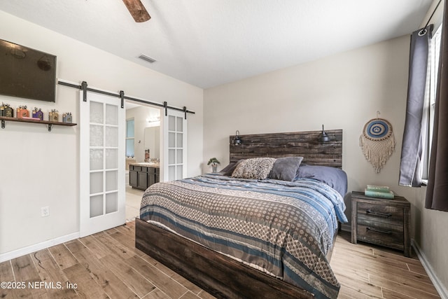 3299 Hidden Meadows Ct, Green Cove Springs, FL 32043 - bedroom with a barn door, wood finished floors, ceiling fan, and ensuite bath
