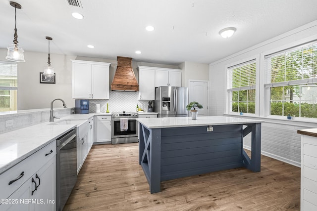 3299 Hidden Meadows Ct, Green Cove Springs, FL 32043 - kitchen featuring appliances with stainless steel finishes, custom exhaust hood, white cabinetry, light stone countertops, and light wood-style floors