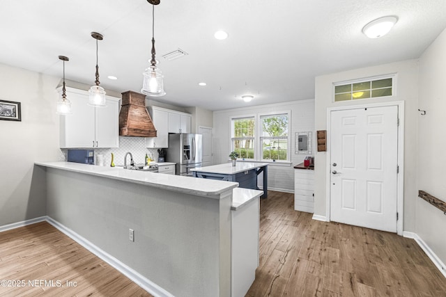 3299 Hidden Meadows Ct, Green Cove Springs, FL 32043 - kitchen featuring stainless steel fridge with ice dispenser, custom exhaust hood, white cabinetry, light countertops, and light wood-style floors