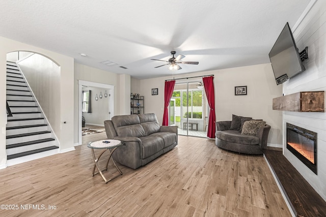 3299 Hidden Meadows Ct, Green Cove Springs, FL 32043 - living area with light wood-style floors, a glass covered fireplace, ceiling fan, and stairs