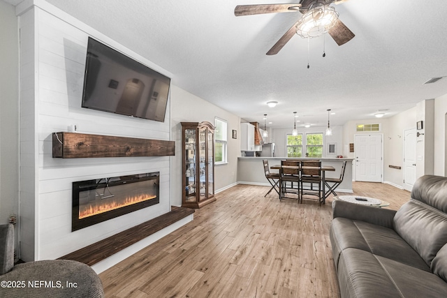 3299 Hidden Meadows Ct, Green Cove Springs, FL 32043 - living area featuring light wood-style floors, a glass covered fireplace, ceiling fan, and a textured ceiling