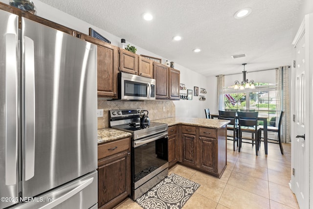 1565 Royal Fern Ln, Fleming Island, FL 32003 - kitchen with stainless steel appliances, a textured ceiling, decorative backsplash, a chandelier, and light tile patterned floors