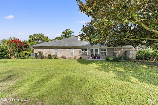 1565 Royal Fern Ln, Fleming Island, FL 32003 - back of house featuring a lawn, brick siding, a patio, a shingled roof, and a chimney