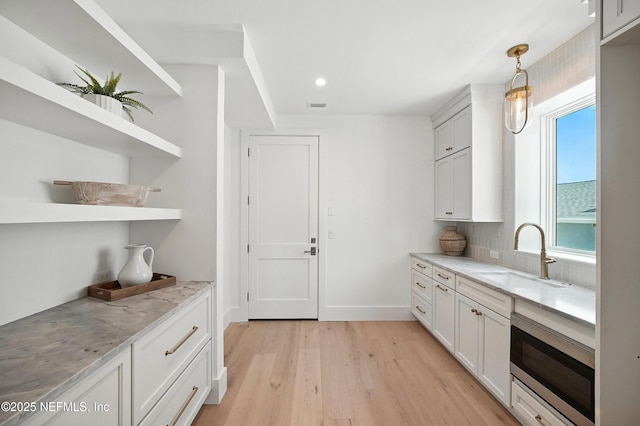 1509 Ocean Front, Neptune Beach, FL 32266 - kitchen with stainless steel microwave, open shelves, light wood finished floors, light stone countertops, and pendant lighting