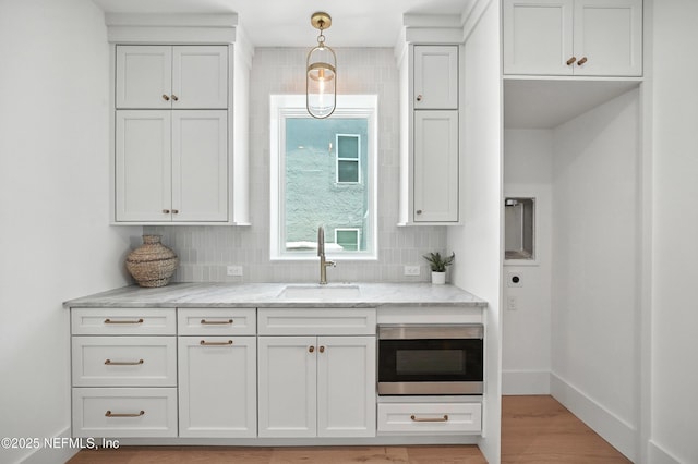 1509 Ocean Front, Neptune Beach, FL 32266 - kitchen featuring light stone countertops, decorative backsplash, light wood-style flooring, and stainless steel microwave