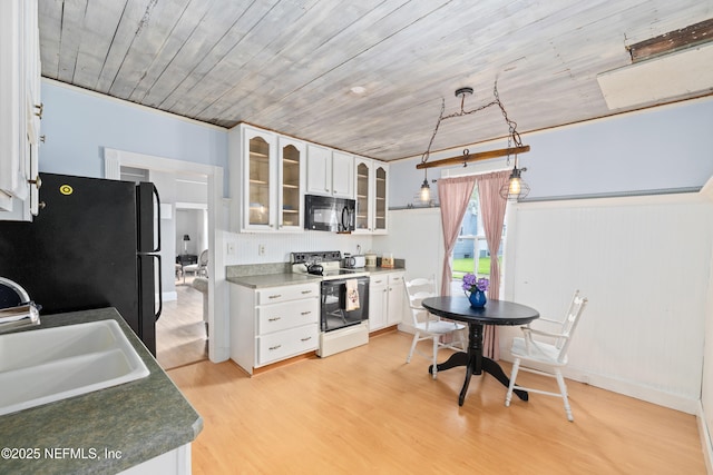 10 Venancio St, Saint Augustine, FL 32084 - kitchen featuring white electric range oven, black microwave, freestanding refrigerator, light wood finished floors, and white cabinets