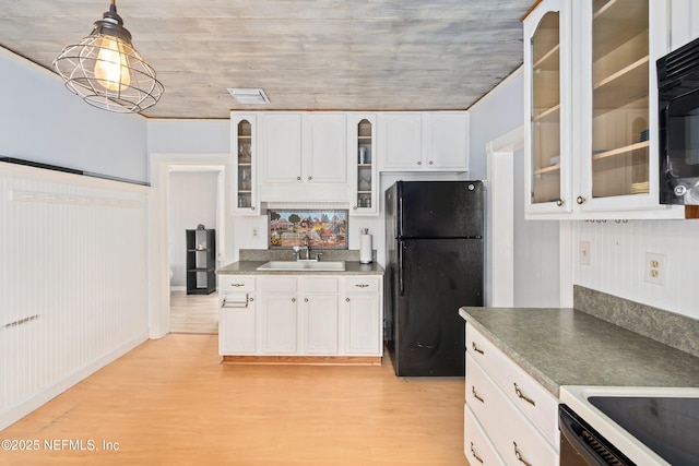 10 Venancio St, Saint Augustine, FL 32084 - kitchen with black appliances, light wood-type flooring, white cabinets, glass insert cabinets, and pendant lighting