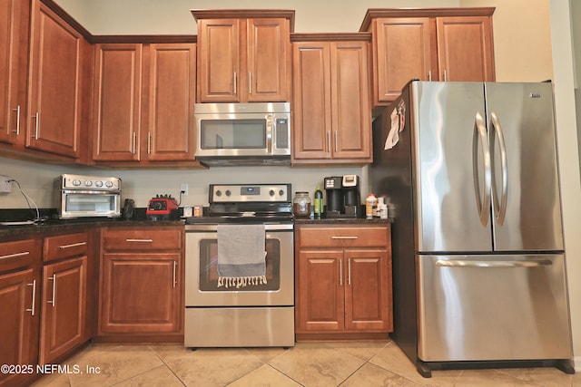 127 Colorado Springs Way, Saint Augustine, FL 32092 - kitchen featuring stainless steel appliances, light tile patterned flooring, dark stone countertops, and brown cabinetry