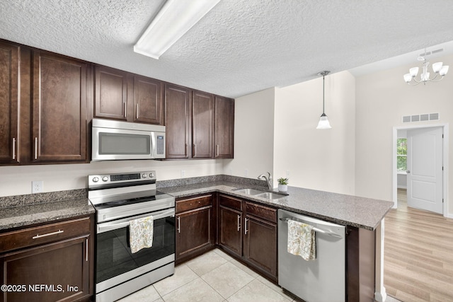 218 Larkin Pl Unit 105, Saint Johns, FL 32259 - kitchen featuring appliances with stainless steel finishes, dark brown cabinets, a peninsula, a chandelier, and decorative light fixtures