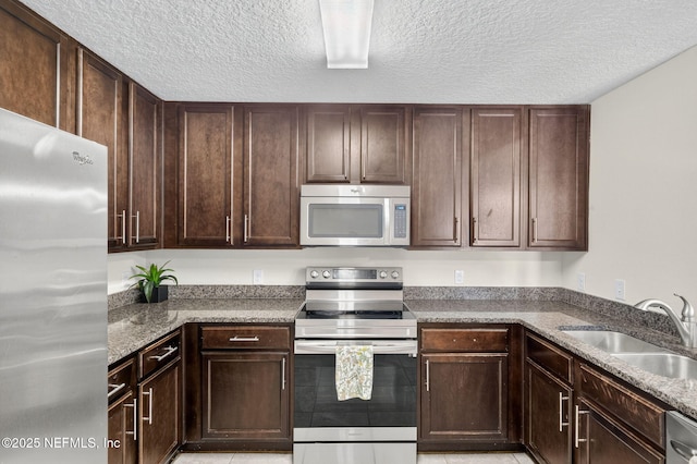 218 Larkin Pl Unit 105, Saint Johns, FL 32259 - kitchen featuring stainless steel appliances, dark brown cabinets, a textured ceiling, stone counters, and light tile patterned floors