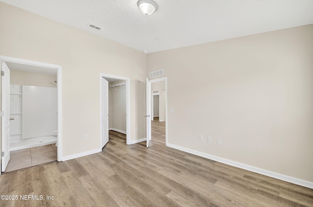 218 Larkin Pl Unit 105, Saint Johns, FL 32259 - unfurnished bedroom with wood finished floors, a walk in closet, a closet, and ensuite bathroom