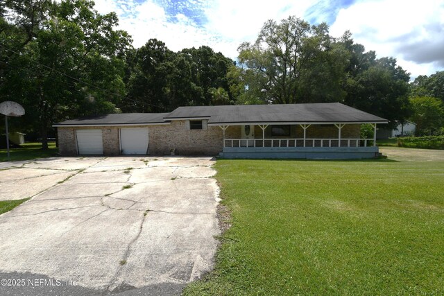 44186 Lee Dr, Callahan, FL 32011 - view of front facade featuring a front lawn, covered porch, driveway, an attached garage, and brick siding