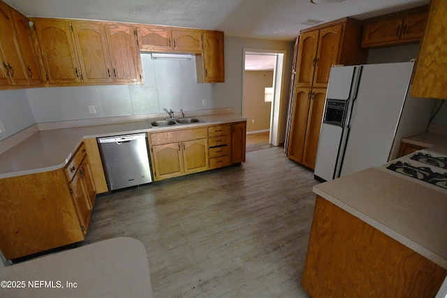 44186 Lee Dr, Callahan, FL 32011 - kitchen featuring stainless steel dishwasher, white fridge with ice dispenser, light wood finished floors, light countertops, and brown cabinets