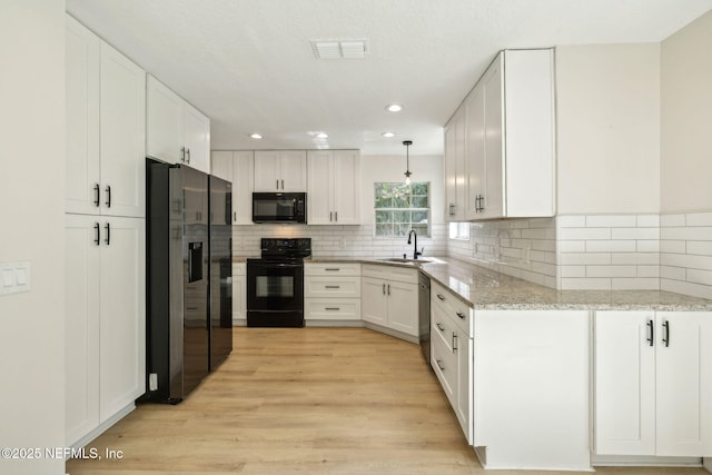 4804 Winton Cir, Saint Augustine, FL 32086 - kitchen featuring black appliances, light wood-style flooring, white cabinetry, light stone countertops, and recessed lighting