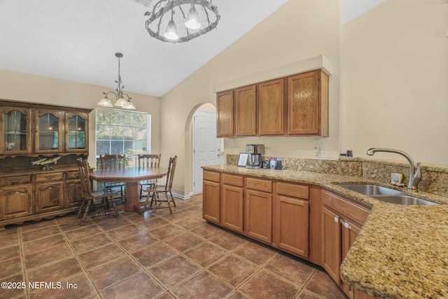 1133 Blue Sky Way, Jacksonville, FL 32225 - kitchen featuring a chandelier, arched walkways, pendant lighting, brown cabinetry, and high vaulted ceiling