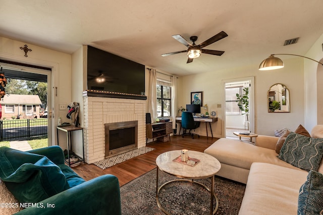 4818 Astral St, Jacksonville, FL 32205 - living room featuring a brick fireplace, wood finished floors, ceiling fan, and plenty of natural light