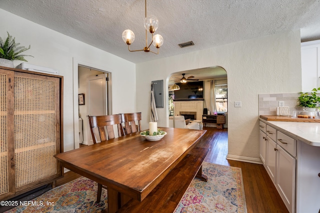 4818 Astral St, Jacksonville, FL 32205 - dining area with a brick fireplace, ceiling fan, arched walkways, dark wood finished floors, and a textured ceiling
